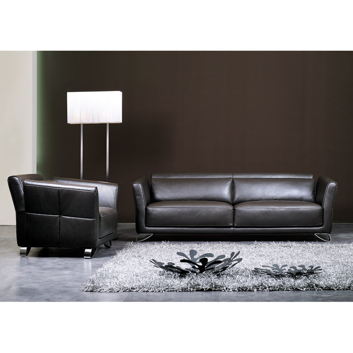 Black leather sofa and armchair in a modern living room setting with a lamp and rug.