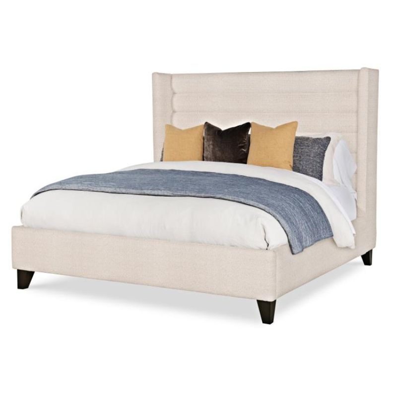 Beige upholstered bed with pillows and a blanket on a white background