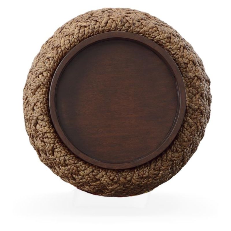 Round wooden tray on top of woven brown end table on a white background