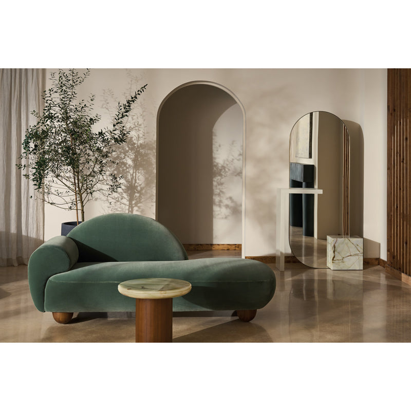 Modern green sofa in a stylish room with mirrors and plants